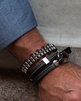 Close-up of a wrist wearing multiple bracelets on a textured surface