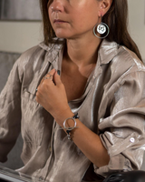 Contemporary Greek coin earrings with a silver-toned pendant, featuring a detailed coin design, worn by a model.