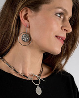 Contemporary statement earrings featuring Greek coin pendants, brass elements, and a sleek, edgy design.