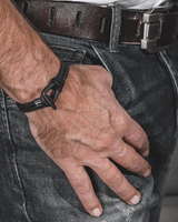 Hand wearing a black bracelet with a blurred background