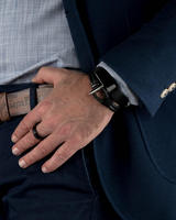Person wearing a navy suit with a brown leather belt and visible buttons.