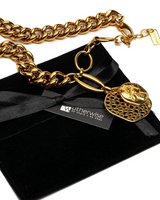 Gold chain necklace with a heart-shaped pendant on a black box with 'otherwise' branding.