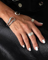 Hand wearing multiple silver rings on a black leather surface