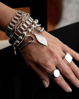 Silver bracelet and ring on a hand against a dark background