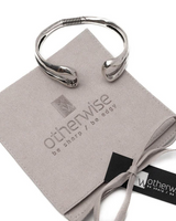 Silver ring on a branded gray cloth with 'otherwise' logo