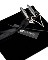 Silver earrings on a black gift box with a black ribbon, branded 'otherwise by hand & by hand'.
