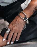 Close-up of a hand wearing silver rings and bracelets with a tattoo on the arm.