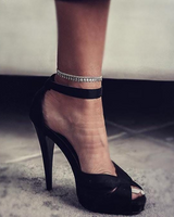 Dainty 999 silver antique plated anklet with charms, worn with a black high-heeled shoe.