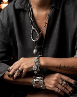 Person wearing multiple bracelets and rings on a textured surface