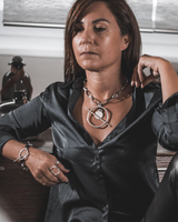 Chunky silver-plated chain necklace featuring a bar closure and a Phaistos disc pendant, styled with a black shirt.