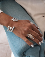 Unisex silver-plated open bangle cuff worn stacked with a statement ring, showcasing a sleek and modern design.