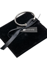 Silver-plated open bangle cuff resting on a black suede pouch, featuring two rounded ends.