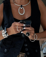 Leather circle pendant choker worn with a sleek black vest, featuring a large geometric brass pendant and adjustable fit.