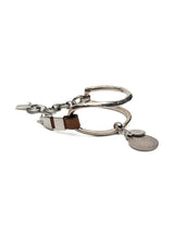 Brown leather wrap bracelet featuring oversized silver-plated horse bit links and coin pendants, adjustable clasp.