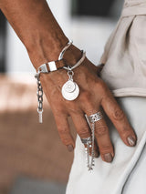 Brown leather wrap bracelet featuring oversized silver-plated horse bit link and coin pendants, adjustable fit.