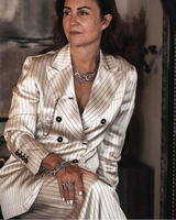 Chunky silver dragonfly pendant bracelet on a model's wrist, paired with a striped suit, showcasing an edgy yet elegant style.