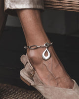 Stainless Steel Teardrop Anklet showcased on a bare ankle, featuring a wavy link chain and a polished teardrop pendant.