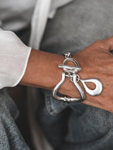 Chunky silver toggle cuff bracelet featuring a heavy, textured design with a T-bar clasp and an oversized drop pendant.