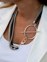 Layered triple chain necklace featuring stainless steel snake chains and a black aluminum chain, large T-clasp detail.