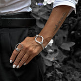 Person wearing silver rings and a bracelet with a blurred background