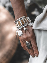 Brown snake-print leather chunky cuff bracelet with silver charms, worn on a hand with a silver ring.