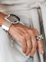Beige leather buckle bracelet with a textured wide cuff design, featuring a prominent silver buckle and adjustable clasp.