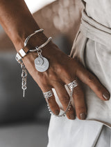 Brown leather wrap bracelet with oversized silver-plated horse bit link, featuring adjustable clasp and coin pendant.