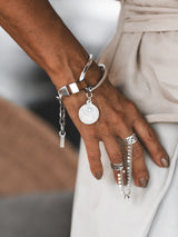Brown leather wrap bracelet featuring an oversized silver-plated horse bit link and coin pendant, worn on a model's wrist.