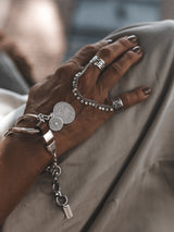 Brown leather wrap bracelet featuring oversized silver plated horse bit link, paired with intricate silver rings.