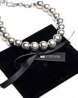Chunky silver ball chain choker with varying bead sizes, displayed alongside a black suede gift pouch.