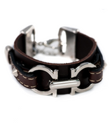 Leather statement bracelet featuring a silver-plated metal design, stitched leather, and decorative studs.