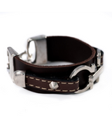 Slightly adjustable leather statement bracelet in dark brown, featuring silver-plated metal design and stud accents.