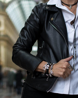 Chunky black leather bracelet with silver-plated accents, worn stacked with other edgy bracelets, styled with a leather jacket.