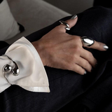 Close-up of a hand wearing two silver rings with a white shirt cuff in the foreground.