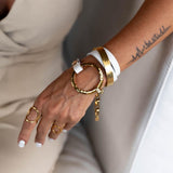 White leather triple wrap bracelet features a hammered gold loop metal and chunky chain, showcasing an edgy style.