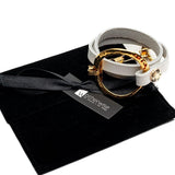 White leather triple wrap bracelet featuring a hammered gold loop and stainless steel chain, presented on a black suede pouch.