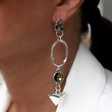 Silver earring with a colorful gemstone worn by a person in a white shirt.