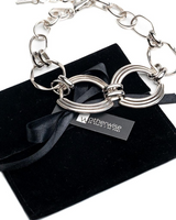 Chunky sculptural collar necklace featuring oversized silver loops on a thick metal band with a lobster claw closure.
