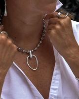Chunky silver ball chain choker with a hammered loop pendant, worn layered over a white blouse.