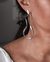 Silver hoop earring worn by a person with a neutral background