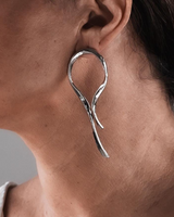 Close-up of a person wearing a silver earring with a neutral background