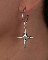 Silver star-shaped earring worn on an ear