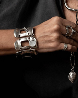 Wide silver-plated zamak arm cuff featuring unique, irregular metal links; adjustable with an extension chain.