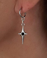 A close-up of a silver crescent moon and star drop earring worn on a person's ear lobe.