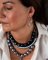 Woman wearing a necklace and earrings with a neutral background