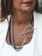 Triple chain necklace featuring steel snake chains and a black aluminum chain, with a large T-clasp for a layered look.