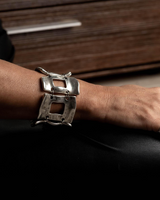 Wide silver-plated zamak arm cuff featuring five unique metal pieces, worn on a wrist with dark nail polish.