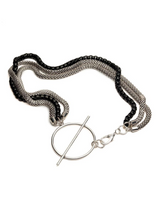 Layered triple chain necklace featuring stainless steel snake chains and a black aluminum chain, large T-clasp detail.
