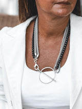 Triple chain necklace featuring stainless steel snake chains and a black aluminum chain, with a large T-clasp detail.