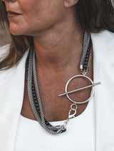 Triple chain necklace featuring steel snake chains and a black aluminum chain, large T-clasp front detail.
